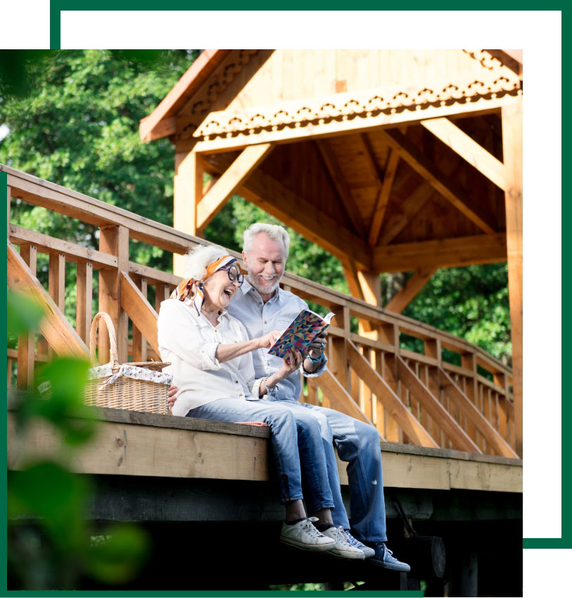 Broad Wealth Management - senior couple happily reading a book while sitting at the garden